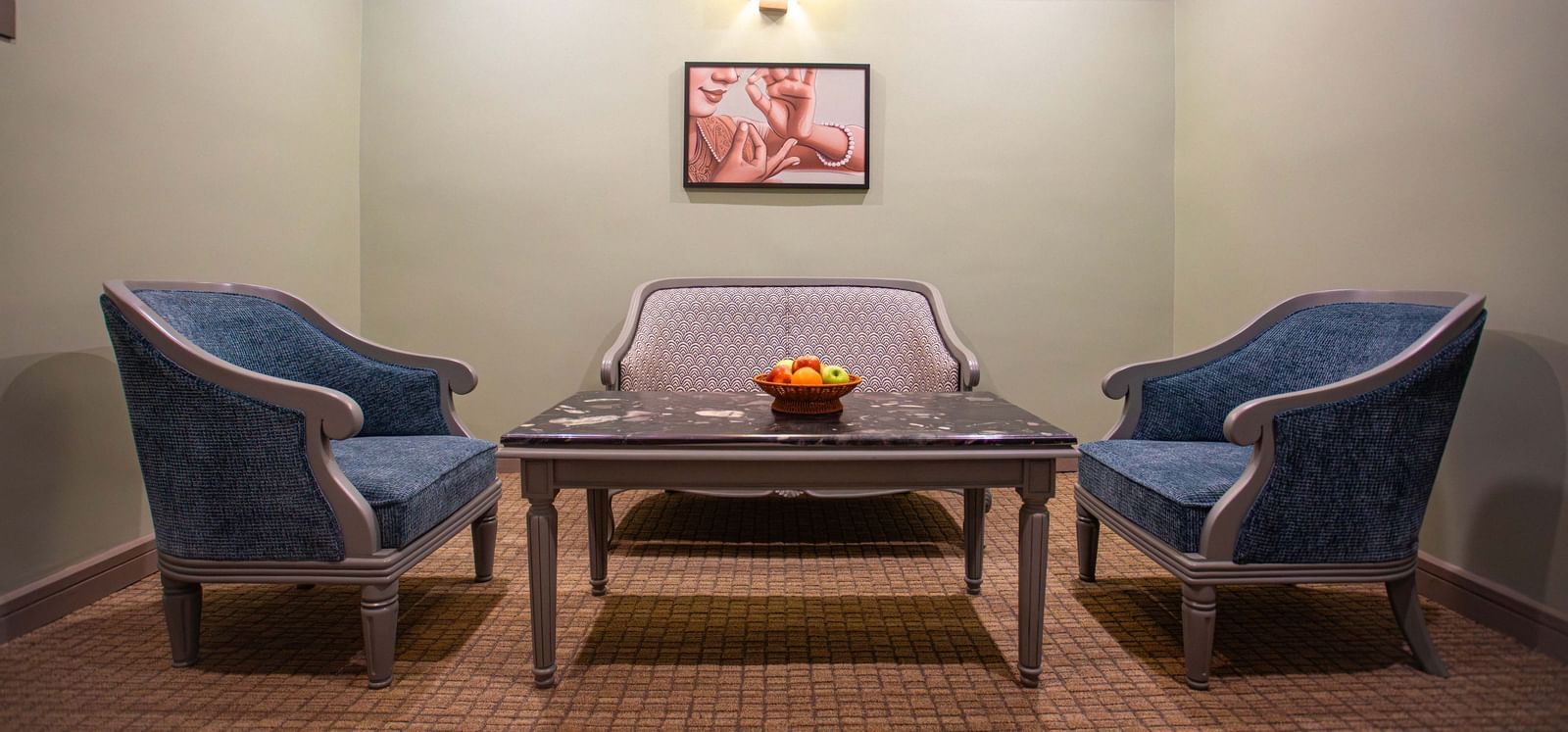 A stylish seating area at Shilton International, Kochi, with two armchairs, a sofa, and a coffee table.