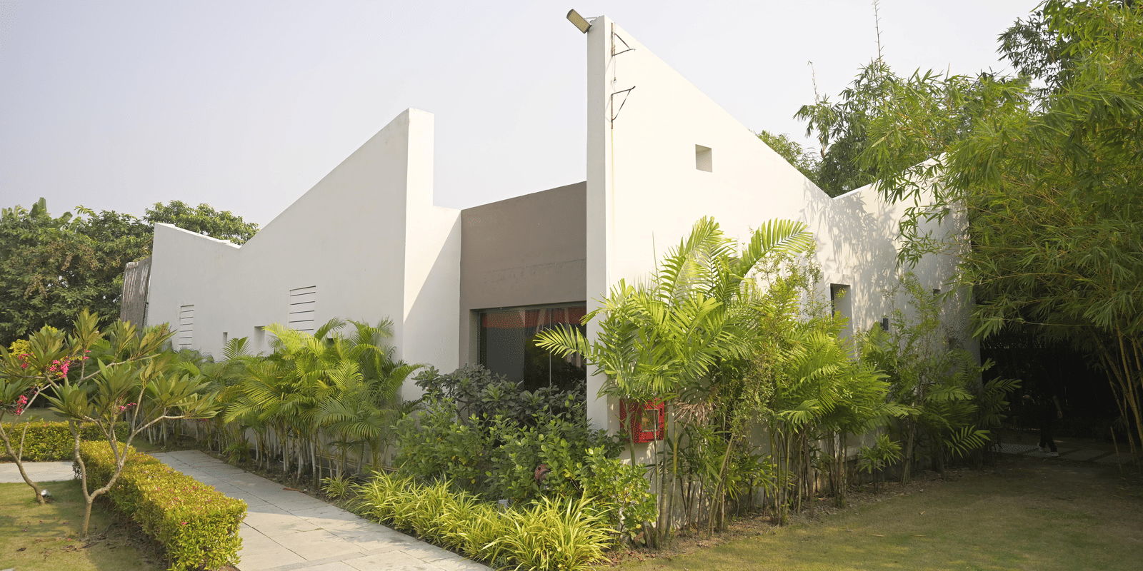 A modern white spa building surrounded by greenery on a bright day at Hotel Sonar Bangla Mayapur.