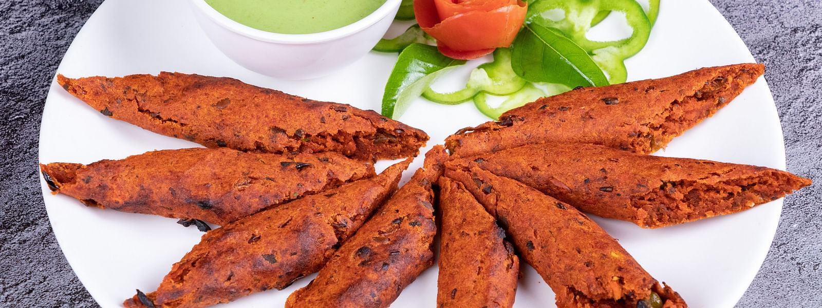 An image of Indian fritters served with a side of mint sauce and salad - The President Hotel, Kumara Park, Bangalore