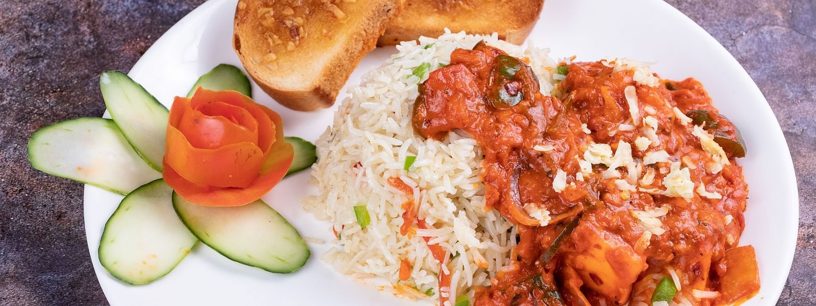 A plate of rice, buttered buns, and chicken curry, garnished with cucumber slices and tomato. - The President Hotel, Kumara Park, Bangalore