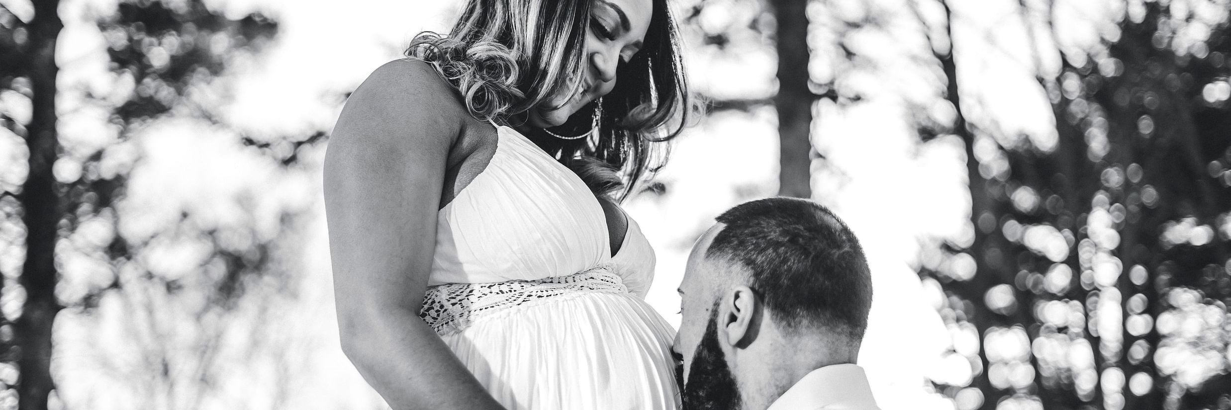 A man kisses his pregnant wife on her belly.