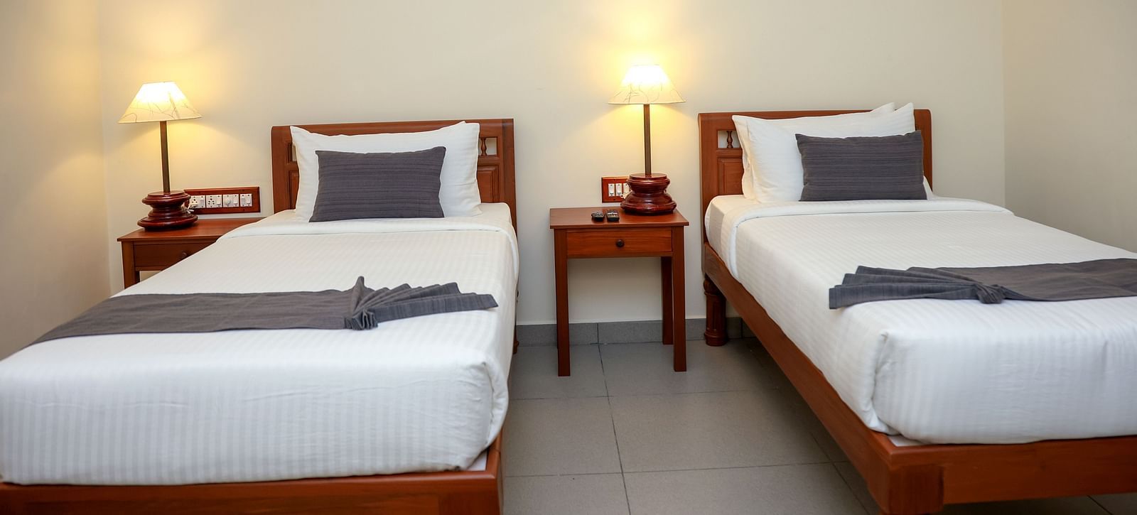 Twin beds with bedside table for each in a room  | Mango Hill La Serene, Pondicherry