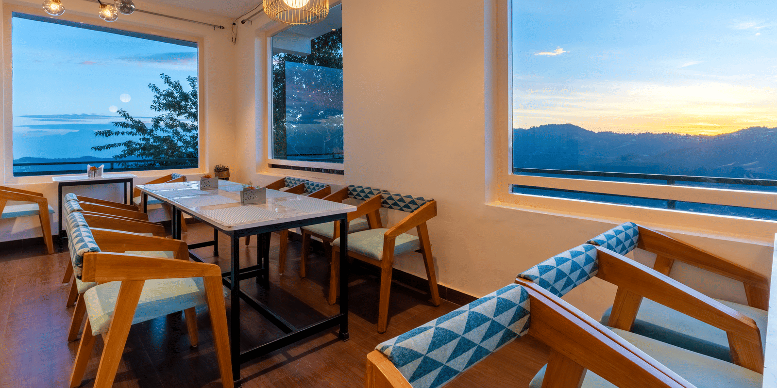 A view of the sunlit dining area with wooden furniture at Himalayas Resort By The Lake Hill, Mukteshwar during sunset.