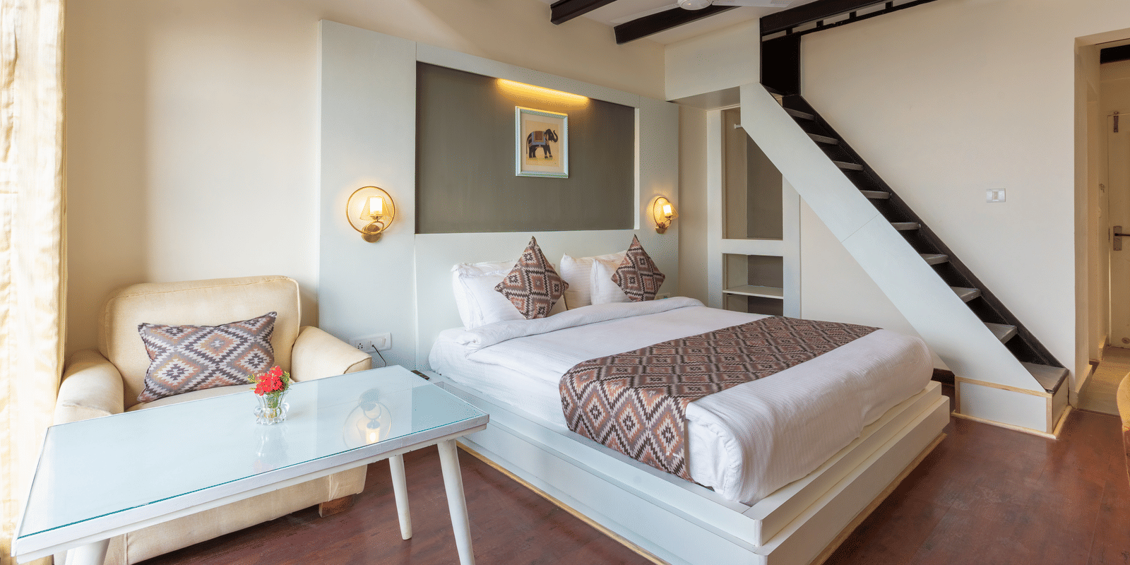 A high-angle view of a guest room with dark wooden ceiling beams and a staircase at Himalayas Resort By The Lake Hill, Mukteshwar.