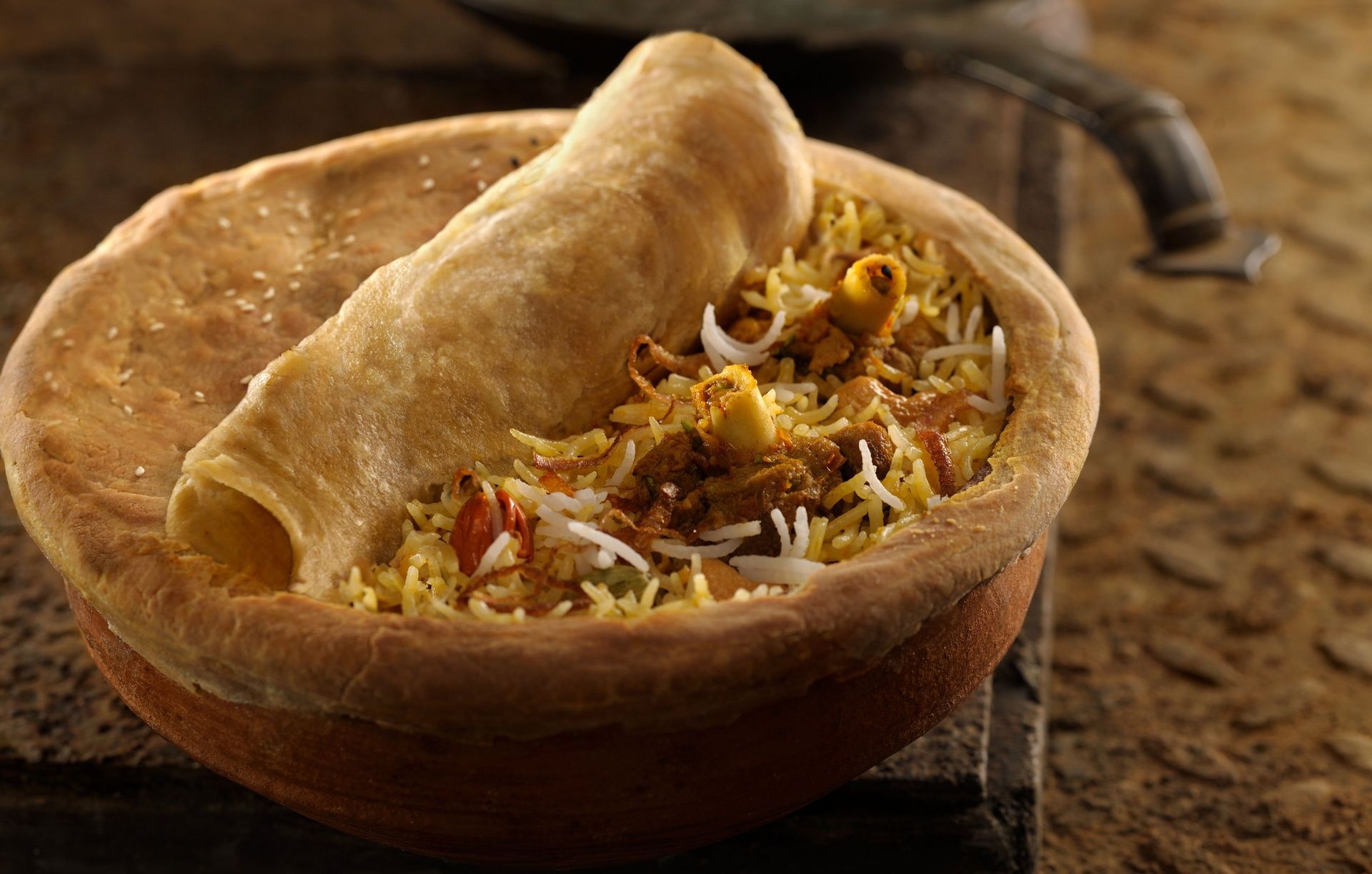 Biryani in a clay pot with a bread seal.