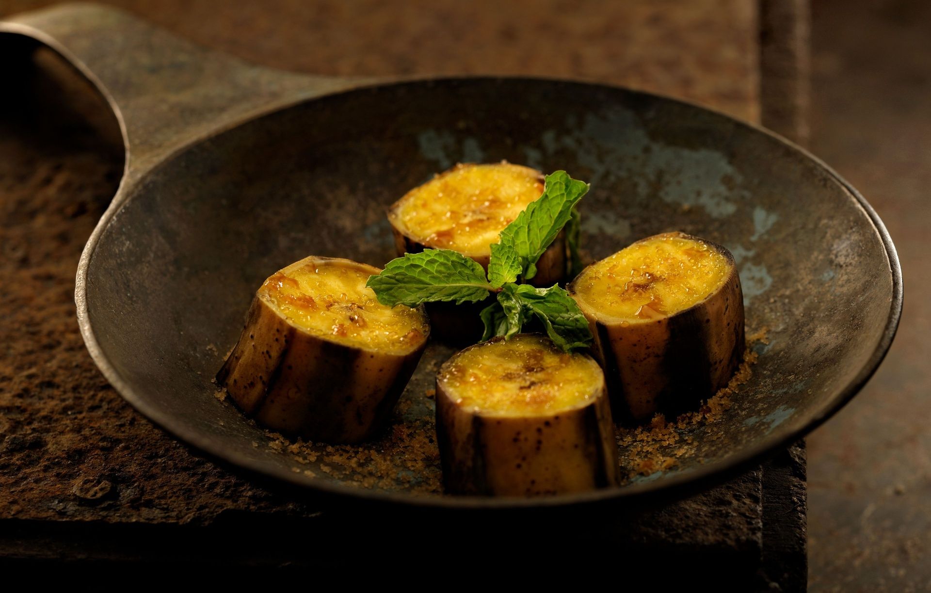 Cooked plantain slices with mint and spices in a pan.