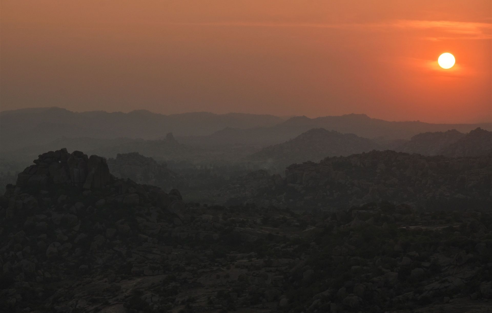 Sunset over rocky hills and ruins at Hampi.