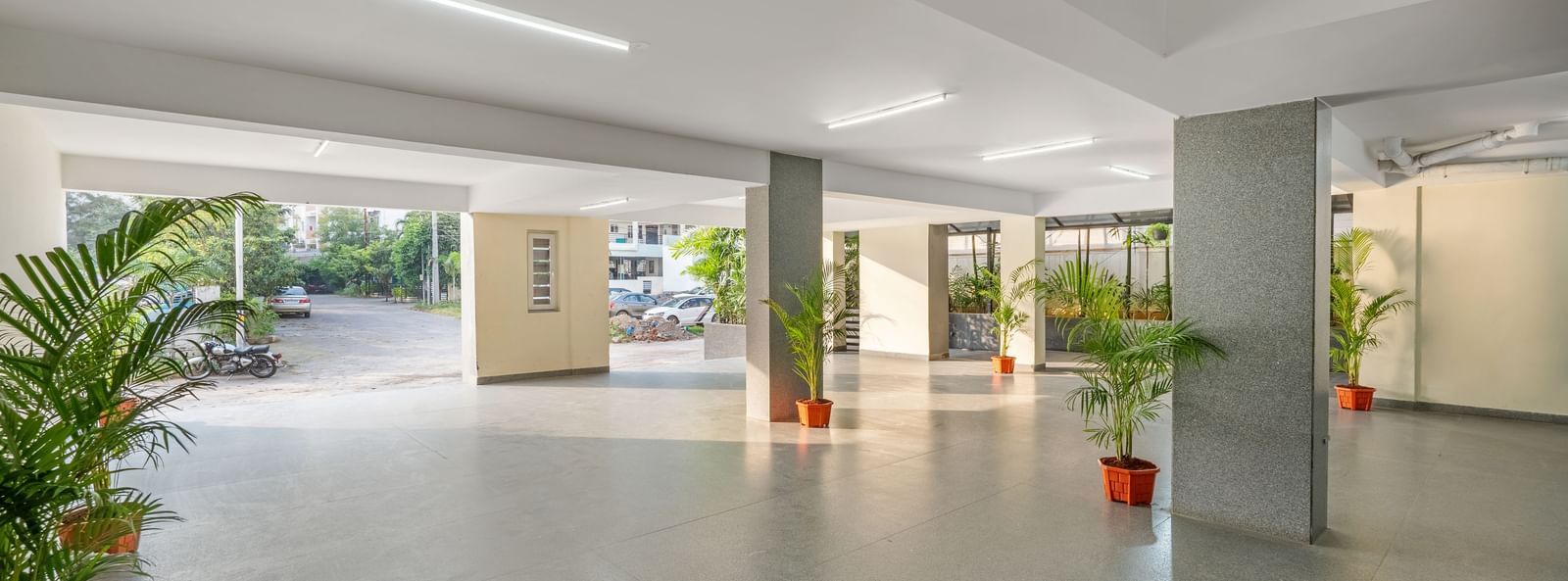 A brightly lit hotel parking area at Destino by Monday Hotels, Gachibowli, with polished floors and potted plants.