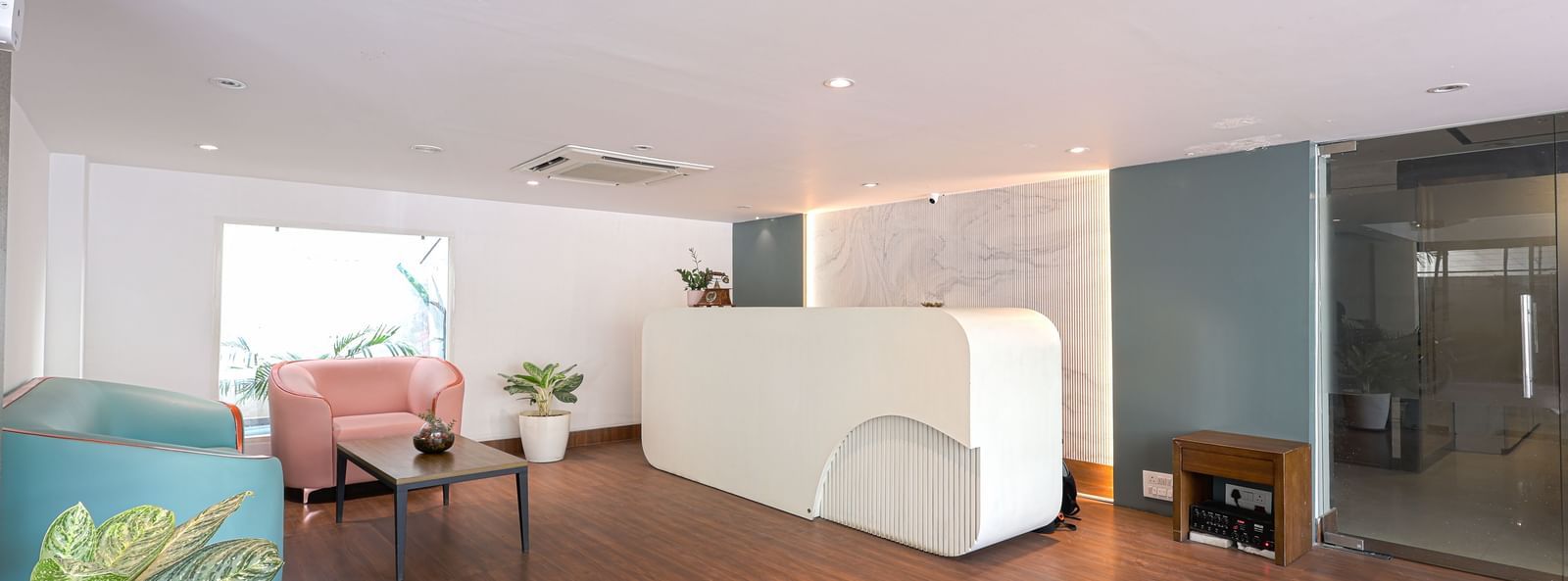 The brightly lit reception area of Destino by Monday Hotels, Gachibowli, with a modern white reception desk and comfortable seating.