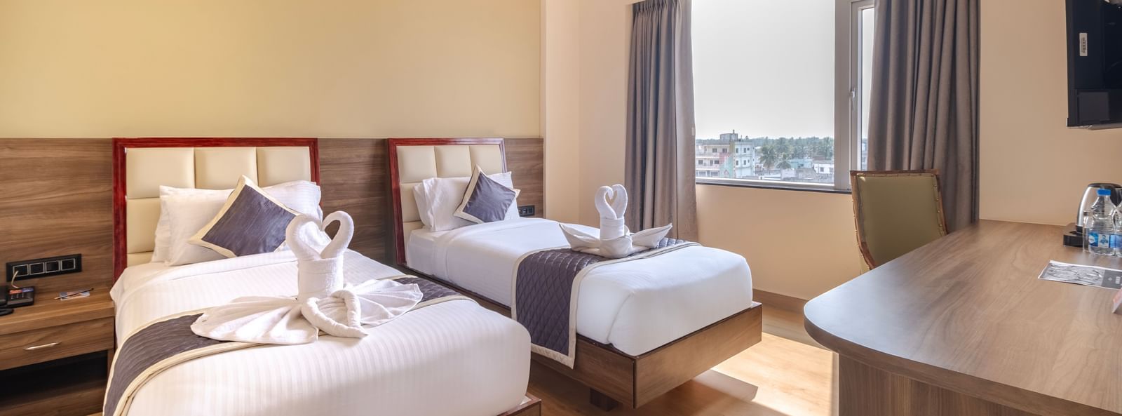 Spacious room at Monday Hotels Amalapuram Heights with warm tones, twin bed, air-conditioning, and window view.