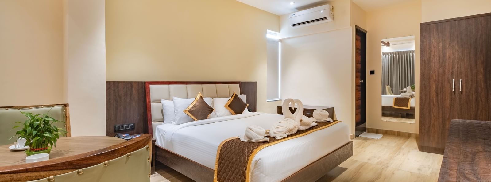 Spacious room at Monday Hotels Amalapuram Heights with double bed, ceiling fan, mirror, and air-conditioning.