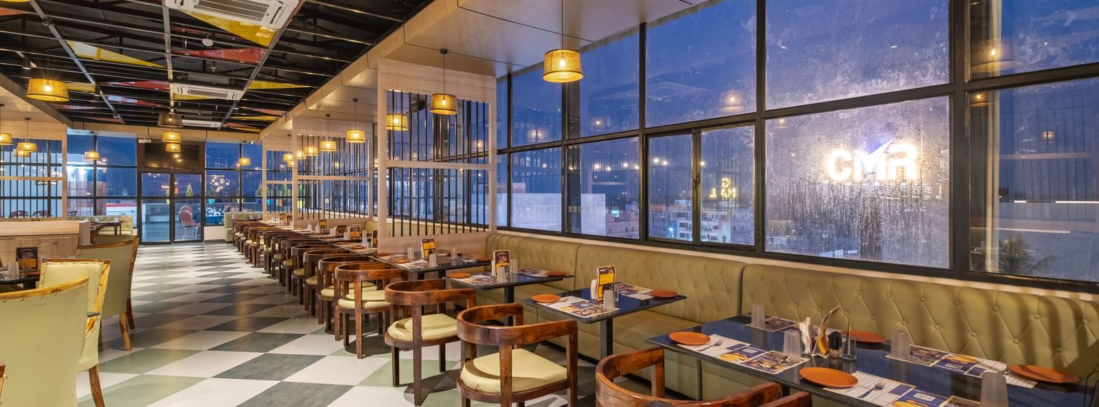 Bright dining hall at Monday Hotels Amalapuram Heights with large glass windows.