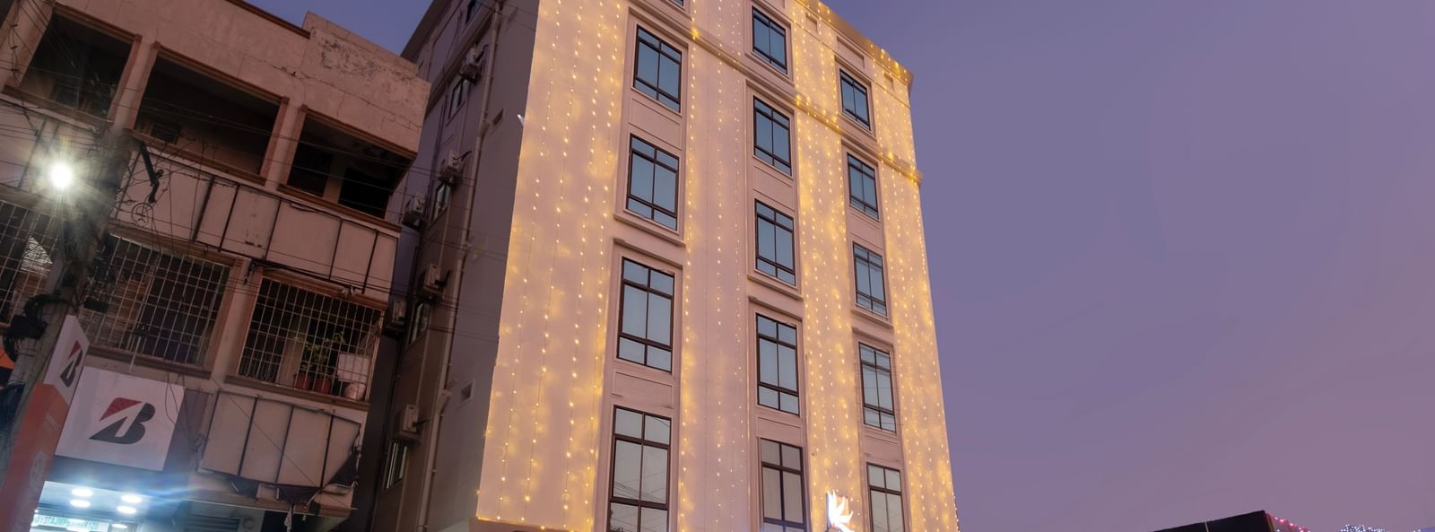 Evening exterior view of Swarna's The Capital with illuminated facade and welcoming entrance.