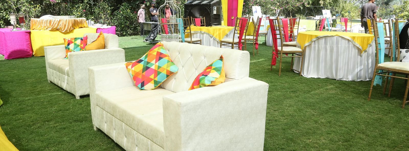 Outdoor seating with couches, colourful pillows, and grass.