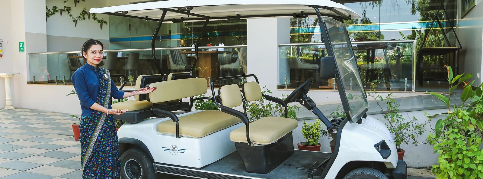 A woman with a golf cart standing outside a building.