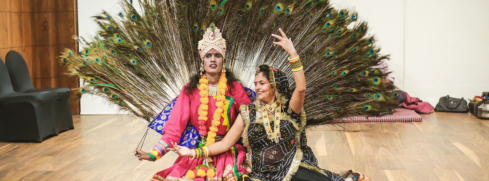 Two dancers in colourful costumes with peacock feather headdress.