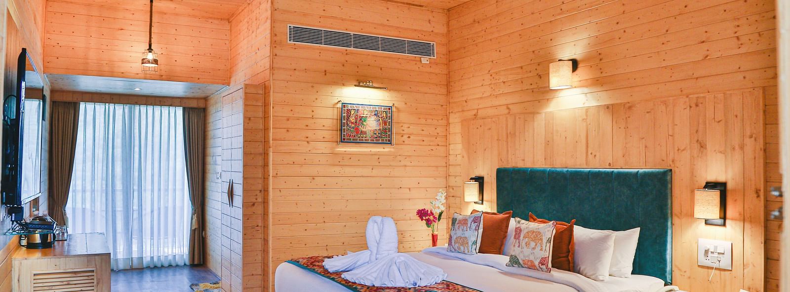 A cosy bedroom with wooden paneling, curtains, a plush bed and warm lighting. - Bamboo Saa Resort & Spa, Udaipur