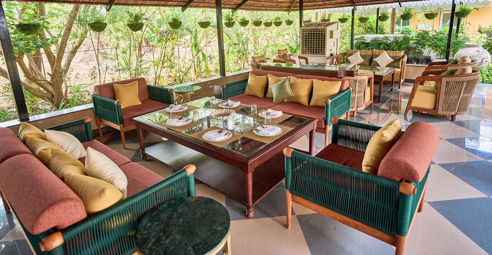 A cluster of cushioned sofas around the table, creating a lounging area at Mayfair Manor, Alibag
