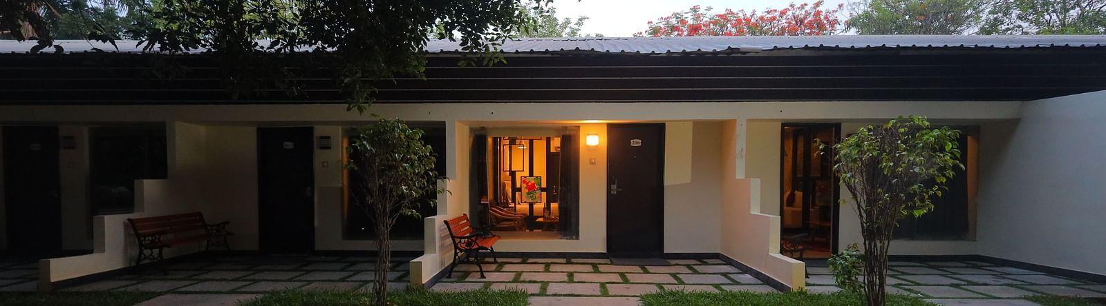 Sathyam Grand Resort featuring building with several rooms opening onto a courtyard with stepping stones, grass, and trees. 