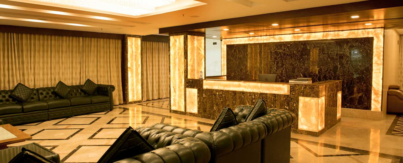 A well-lit hotel lounge at Benzz Park Chennai featuring several comfortable sofas arranged for social gatherings.
