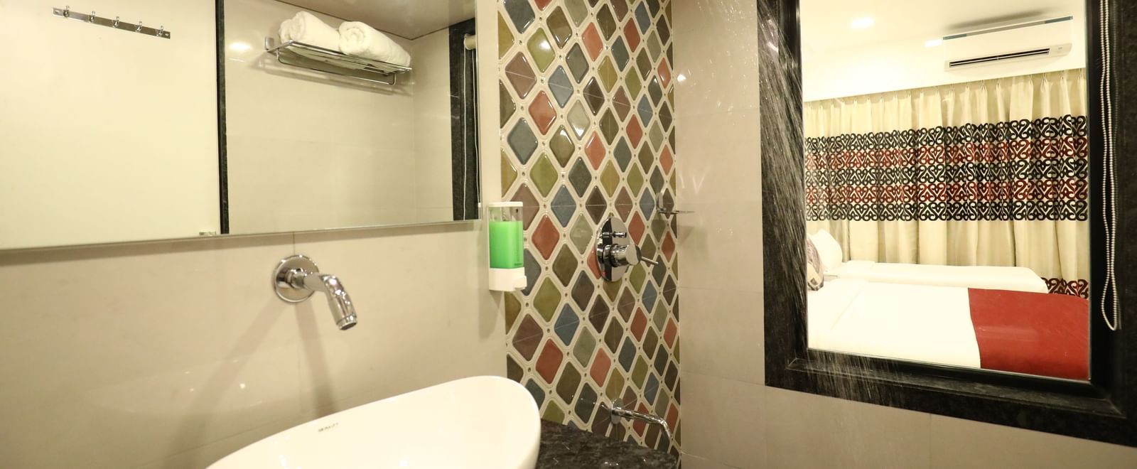  A bathroom at Imperial Grande featuring a white bathtub, a toilet, a sink, and a large mirror with a decorative frame.