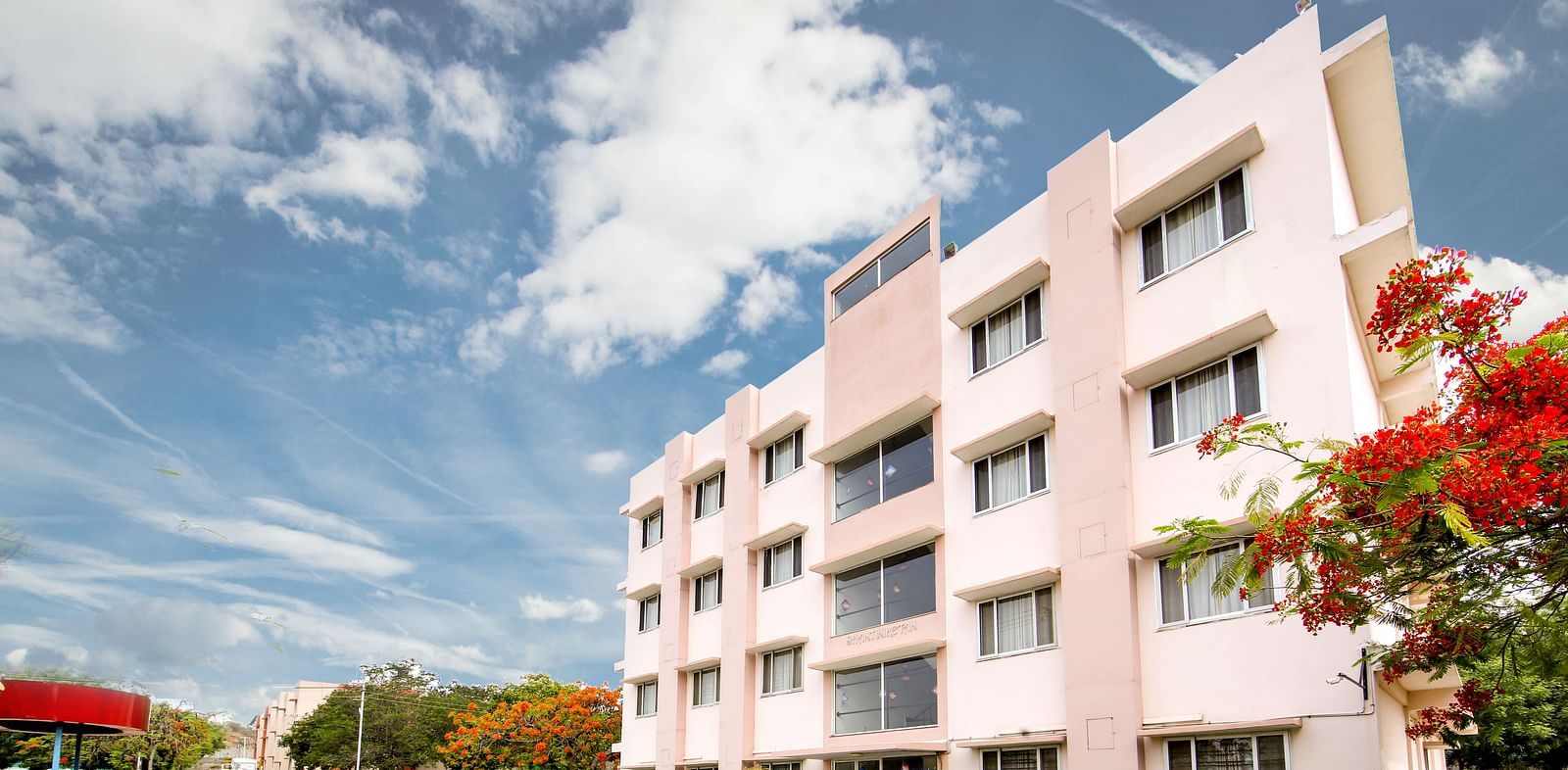 Facade of Greens Inn surrounded by trees - Scenic Hotel in Hyderabad.