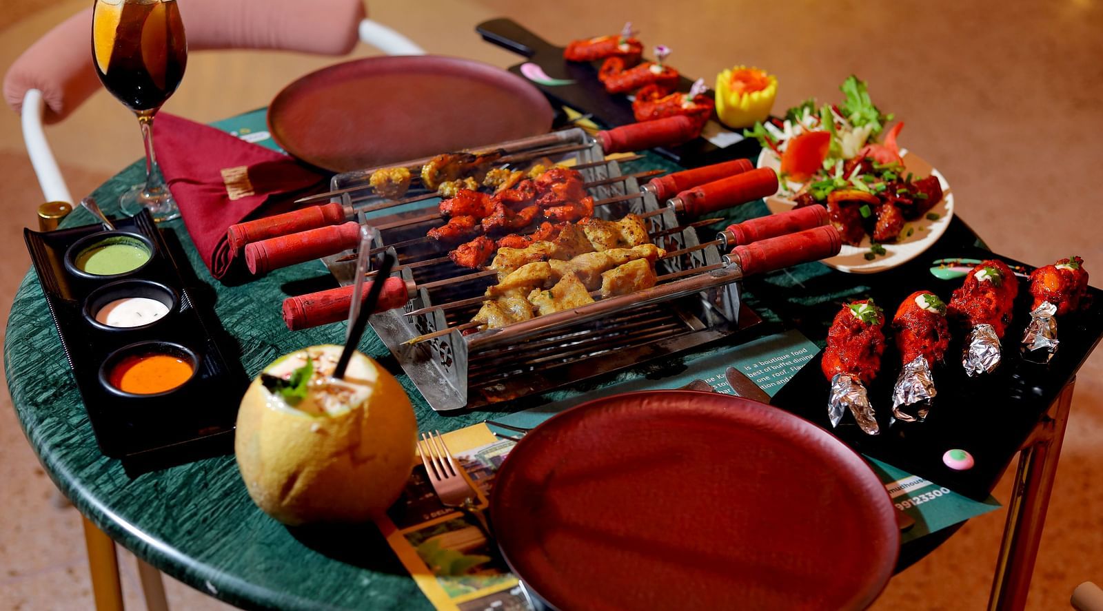 An image of a barbecue table where several eatables are placed like grilled meat, spices, condiments, sauces, dishes, etc at Themis Barbecue House, Ambala