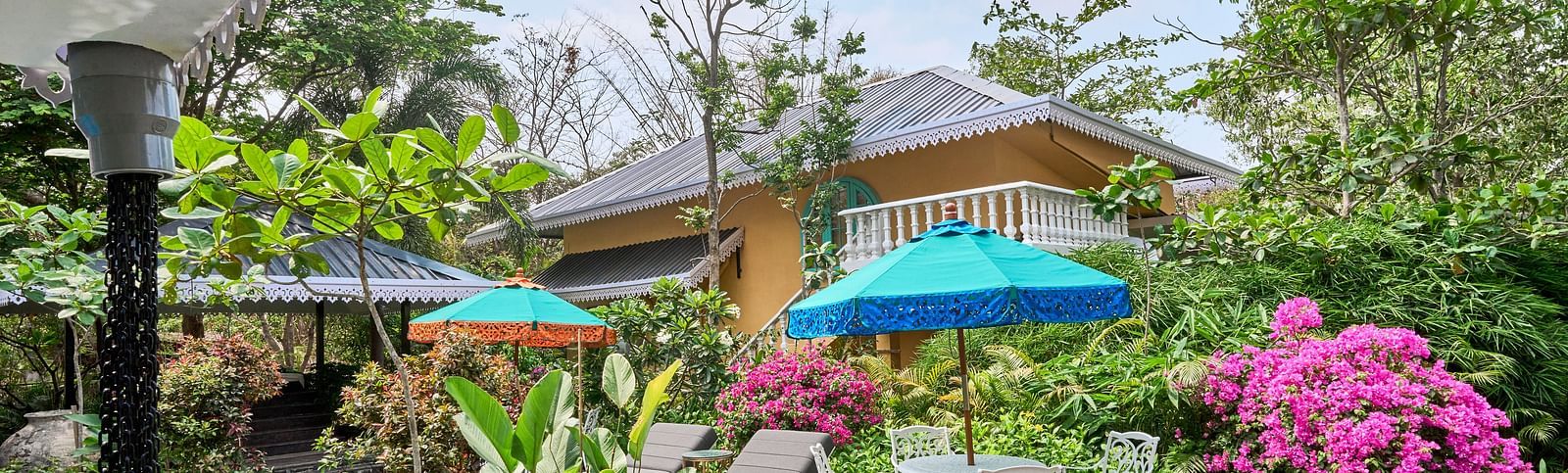 The exterior view of Mayfair Manor, Alibag, framed by trees and plants surrounding the property