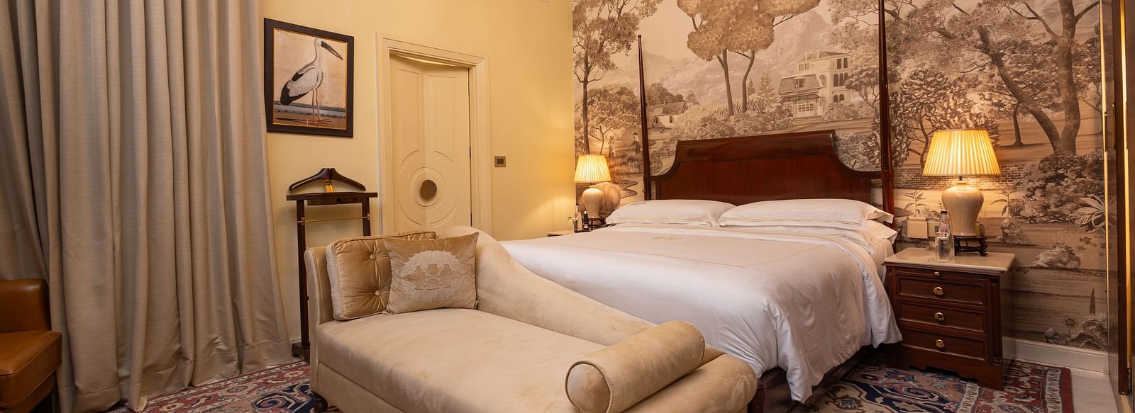 image of a bedroom at our heritage room with a brown scale wallpaper with lush trees - The Claridges New Delhi 