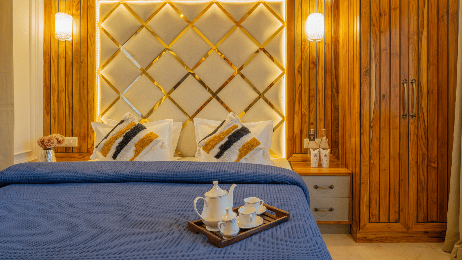 A bedroom with a king size bed, 2 pillows, a bedside table, and a wooden cupboard at Perfectstayz Value Paradise, Mussoorie.