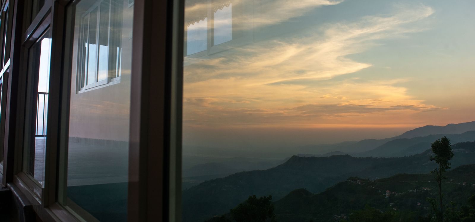 A facade image showing a window with reflection of the Himalayan mountains - Avianna Windy House Wellness Retreat & Spa