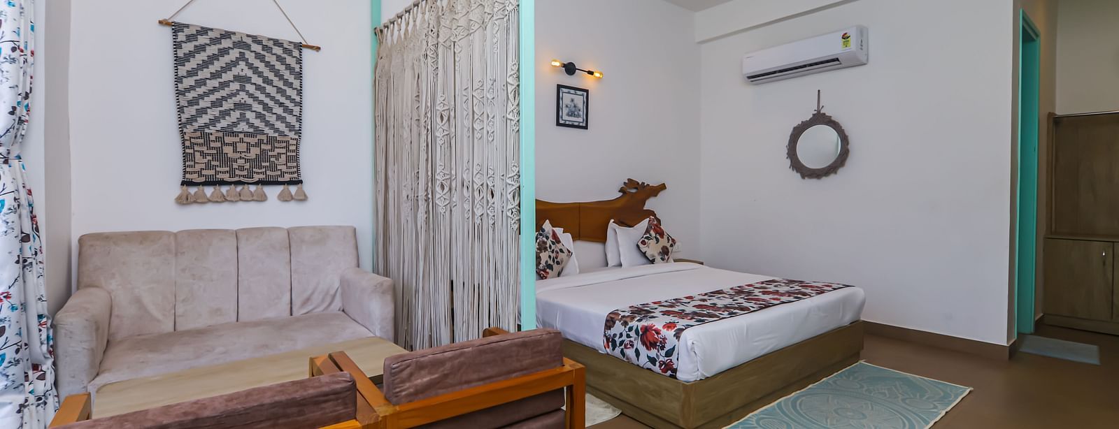 Inside view of a room at Vedikant Resorts The Mallard Corbett with a bed, bench, large window, and a wall art feature.