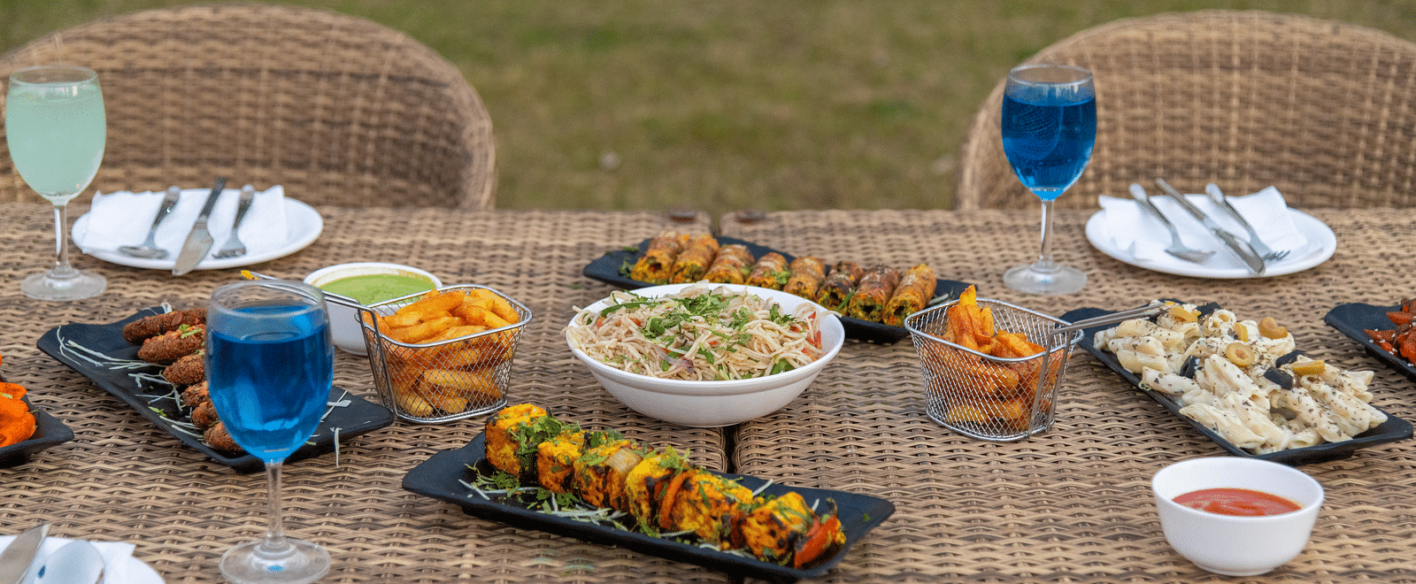 Outdoor dining setup with food and beverages on a long table at DLS Park Grace, Haridwar.