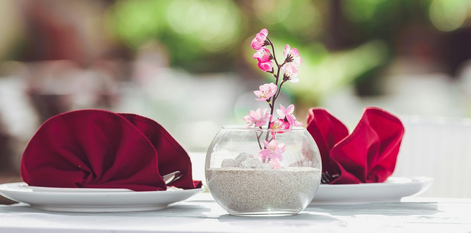 A bright daytime table setting with red napkins and a simple floral centerpiece at Ramoji Film City in Hyderabad 