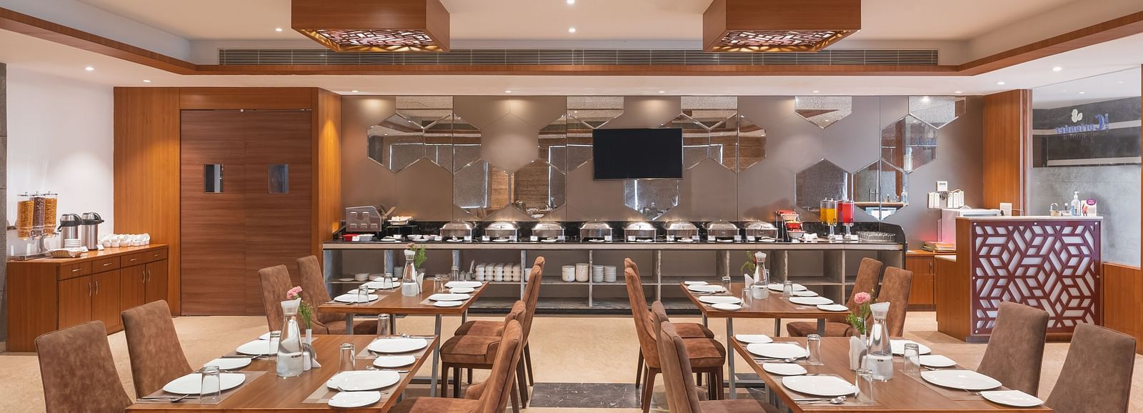 The spacious restaurant at Lords Inn Udaipur is set with multiple tables and chairs, featuring a buffet area in the background.
