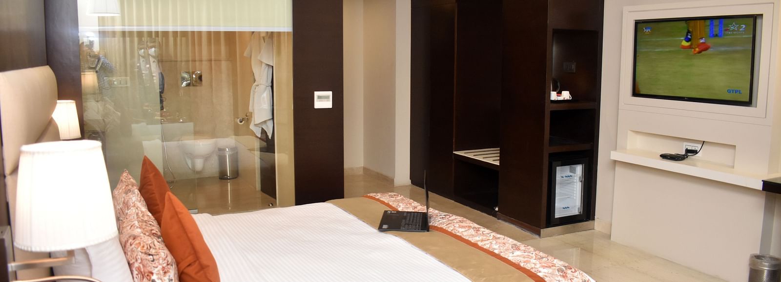 A glimpse into a hotel room showing a bed and an open bathroom at Lords Plaza Surat.