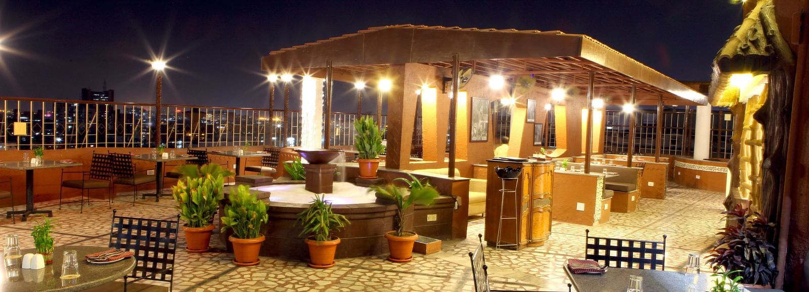 An outdoor seating area with covered structures at night at Lords Plaza Surat.