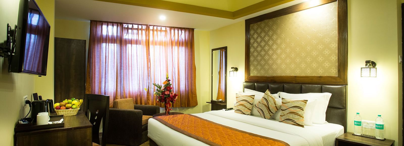 A hotel room at New Orchid Lords Inn Gangtok with a bed, furniture, and a window.