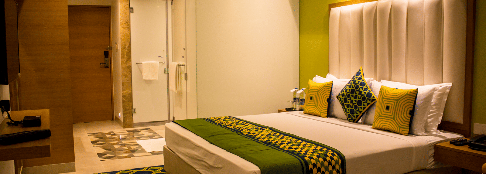 A room with a bed and  pillows arranged on it  along with  a side table | Regency Tirunelveli By GRT Hotels