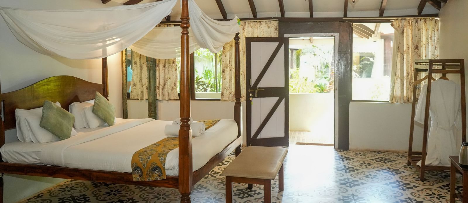 Cosy bedroom with canopy bed and large windows letting in natural light at De Soul Santé, Morjim.