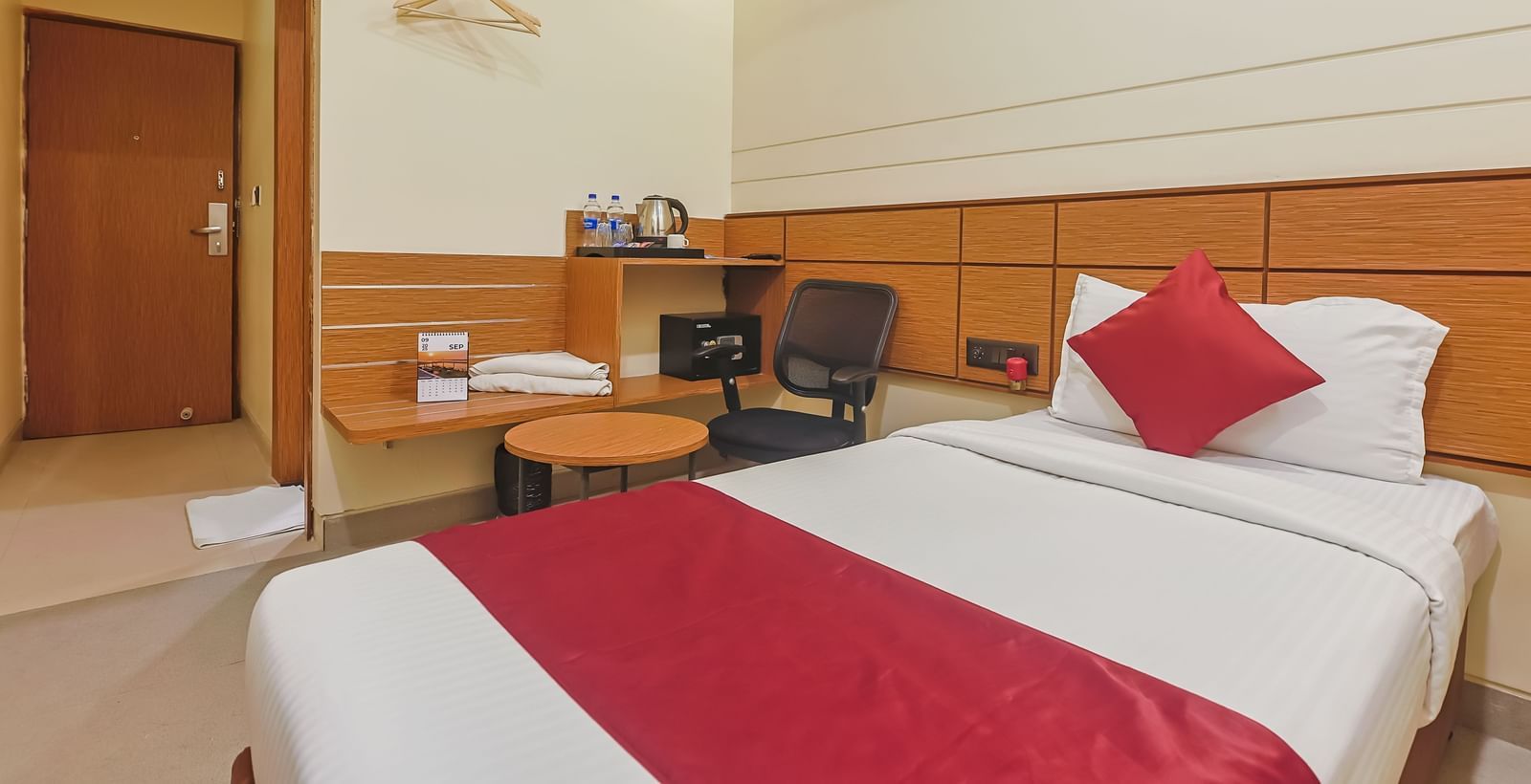 Bright twin-bed setup with wooden furniture at Max Hotel Prayagraj.