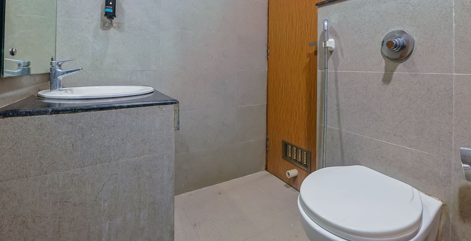 Bathroom with wash basin, mirror, shower area and toilet at Max Hotel Prayagraj.