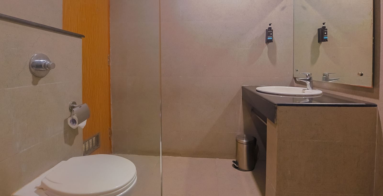Bathroom with toilet, wash basin and mirror at Max Hotel Prayagraj.