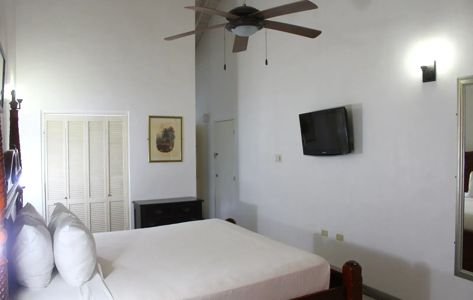 A hotel room with a single bed, a ceiling fan, and a wall-mounted television | Executive King Room | Altamont Court, Jamaica