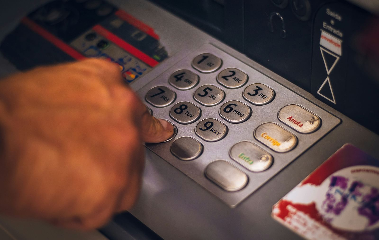 A close-up shot of a person typing buttons into n ATM Machine - Hotel 39, Jamaica
