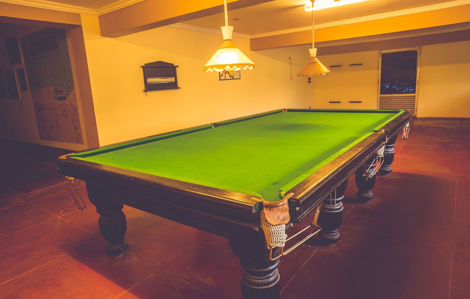A view of a snooker table lit up by warm lights in the gaming room at Paradise Isle Beach Resort, Udupi