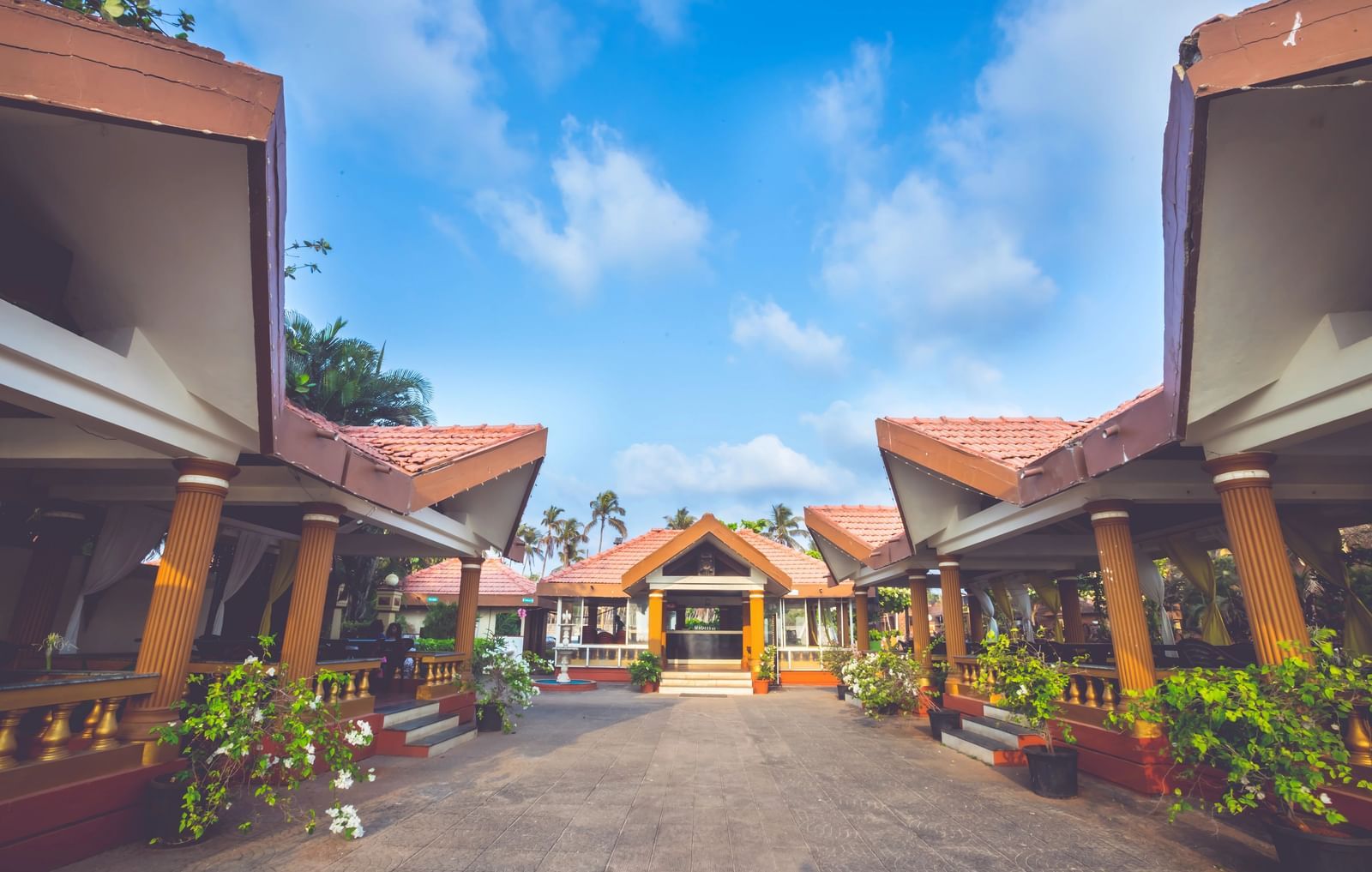 A bright, wide-angle shot of Paradise Isle Beach Resort's entrance, featuring two identical covered walkways leading to a central building.