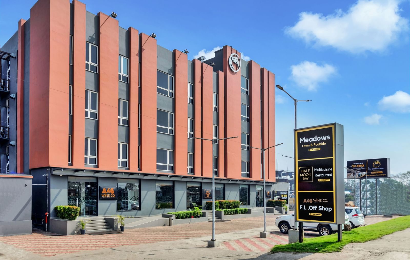 A modern, multi-story hotel building with orange and grey facade under a blue sky with scattered clouds  | The Citi Residenci Hotel Banskopa