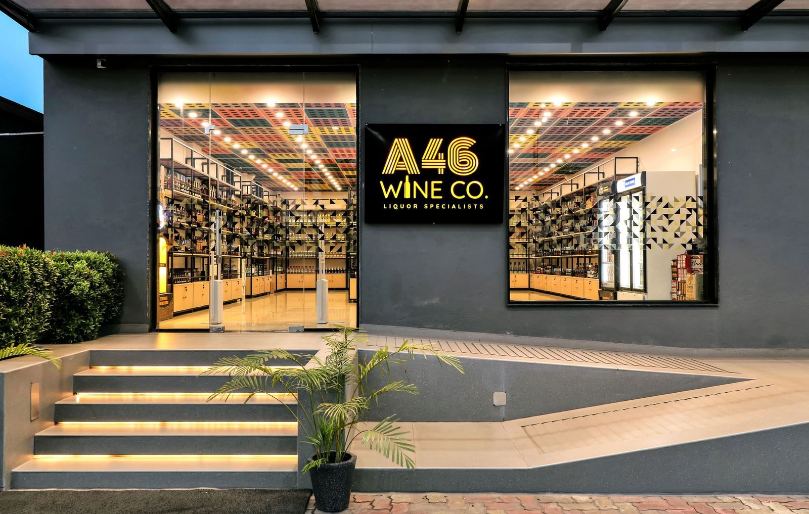 The exterior of a wine shop named A46 Wine Co with large windows displaying rows of wine bottles | The Citi Residenci Hotel Banskopa