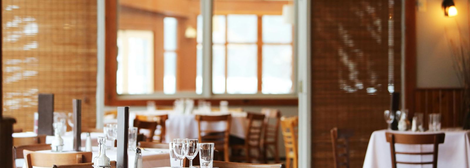 A restaurant interior with tables set with white tablecloths and chairs.